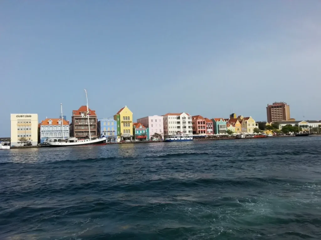Colorful waterfront buildings in Willemstad, Curaçao with a view of the sea and a docked boat.