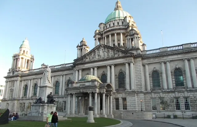 Historic Belfast City Hall with statues, showcasing Edwardian architecture under a clear blue sky.