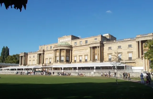Buckingham Palace garden view on a sunny day with visitors enjoying the surroundings.