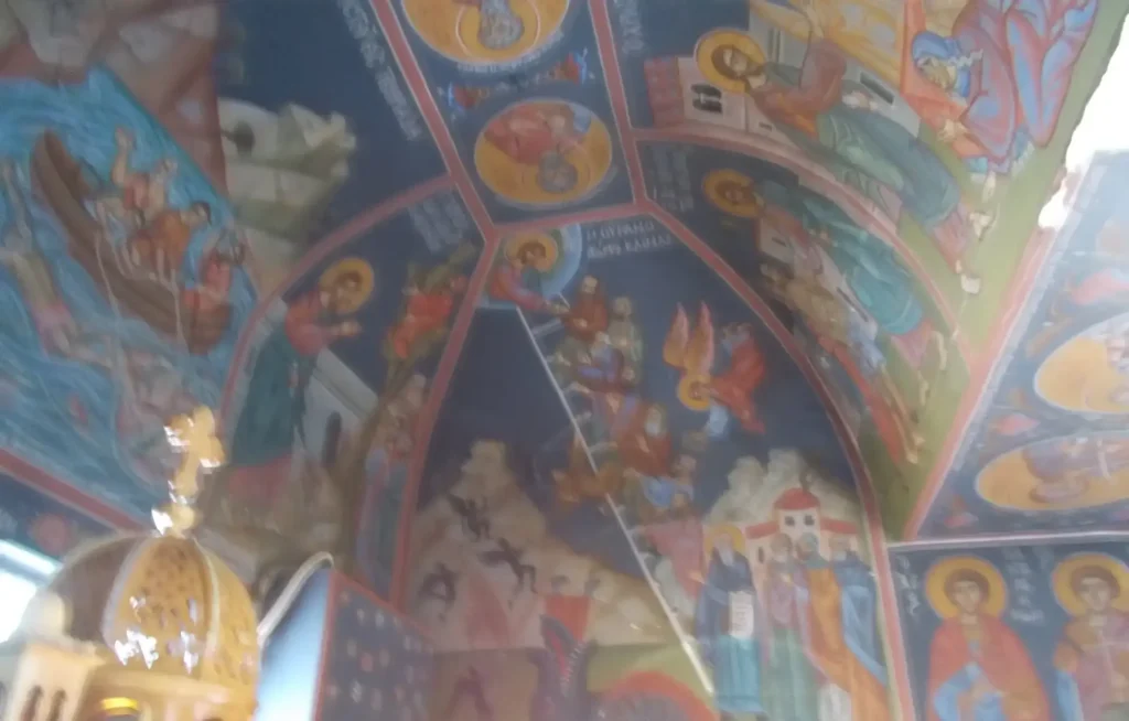 Ceiling of a church adorned with vibrant religious frescoes and intricate iconography.