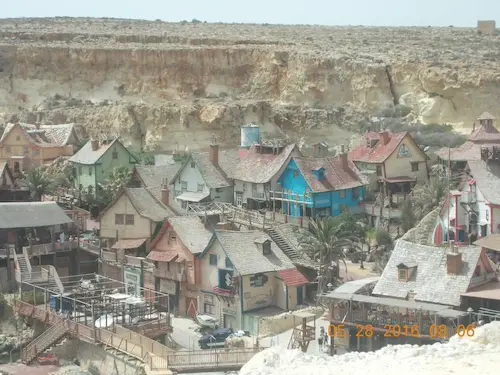 Colorful village houses under rocky cliffs at Popeye Village, Malta.