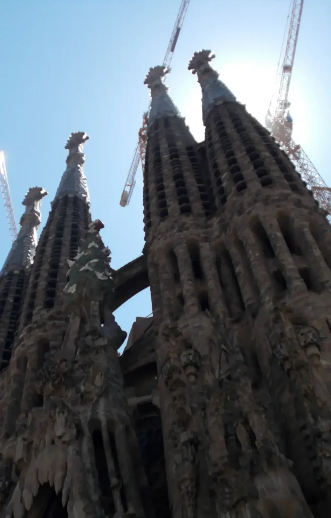 Sagrada Familia in Barcelona with cranes in the background on a clear day.