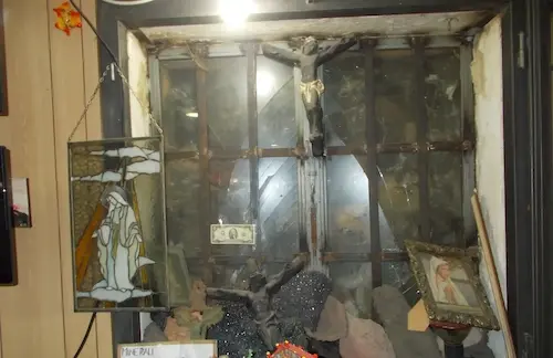 Cluttered window with stained glass art, currency, and framed pictures, creating an eclectic, vintage aesthetic.